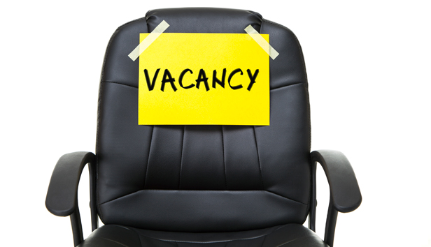 A black leather office chair with a sign stating vacancy taped to it