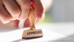 A hand holds a stamp labeled "approved"
