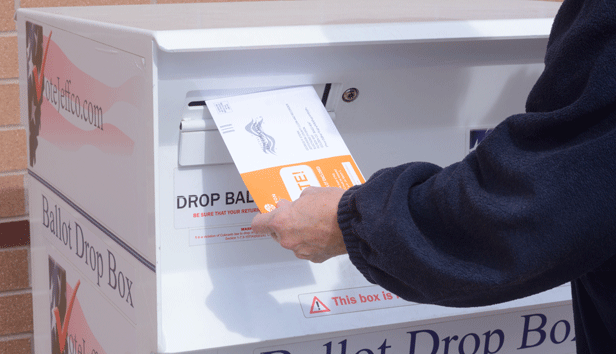 A person putting a ballot into a ballot box