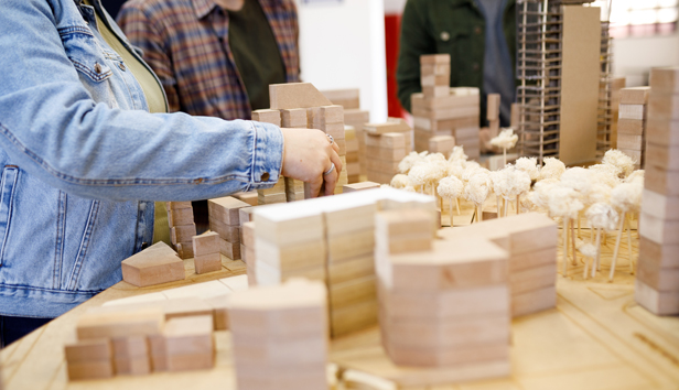 Three people work on an architectural model of a small city
