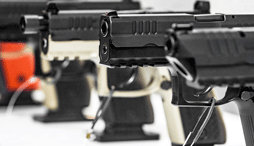 A close up of 3 secured pistols on display