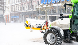 A snow tractor plowing a small town street