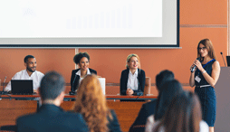 A candidate forum with three candidates and a moderator in front of an audience