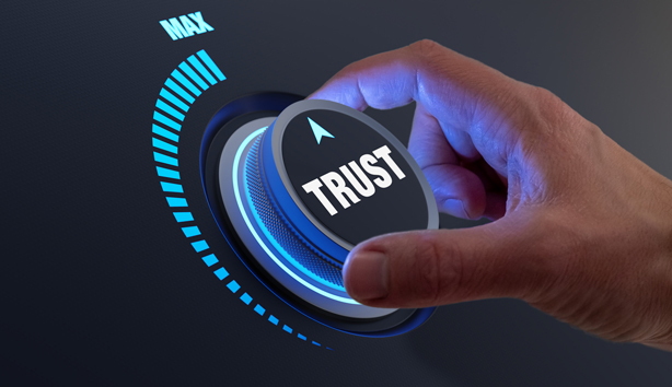 a hand turning a dial to maximum 'trust' 