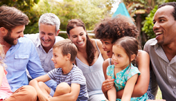 A diverse group of happy adults and kids sitting in a garden