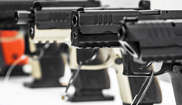 A close up of 3 secured pistols on display